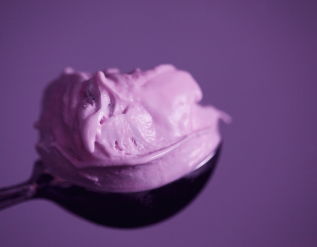 Colher para sorvete preenchida com uma porção de sorvete roxo.